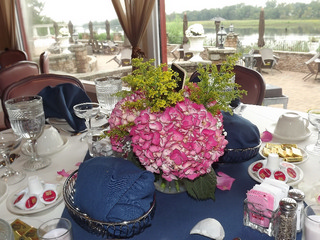 Tablescape, white table cloth, blue napkins and pink flower center piece.