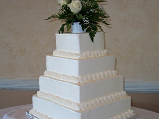 4 tier square while wedding cake topped with white roses.