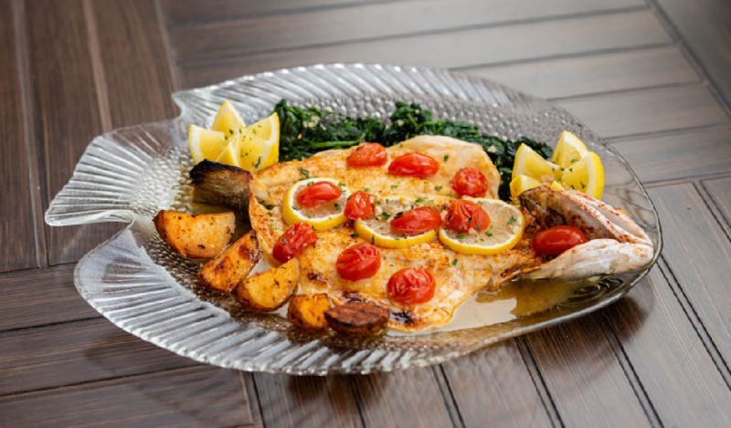 Outdoor table with clear fish shaped with a fish, tomatoes, lemons and potatoes