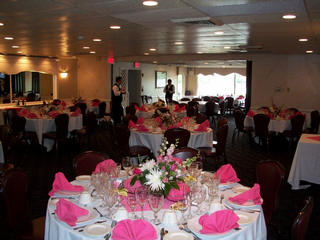 Sunset room banquet setup with white table cloths, red backed chairs, pink napkins.