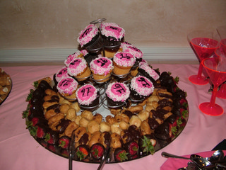 Sweet 16 birthday party setup, chocolate cupcake with pink frosting, surround by pastries and chocolate covered strawberries.