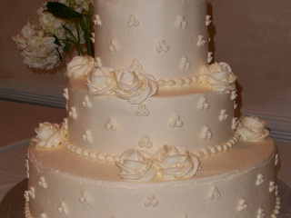3 tier round white cake accented with white dots and white icing roses.